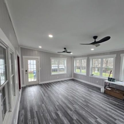 Modern white kitchen with stainless steel appliances, white countertops, and wood floor.