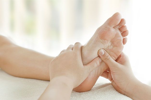 Eine Person bekommt von einem Masseur eine Fußmassage.