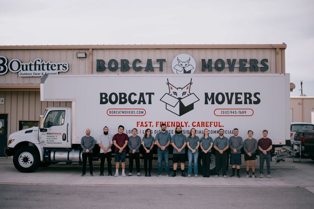 A group of people standing in front of a bobcat movers truck.