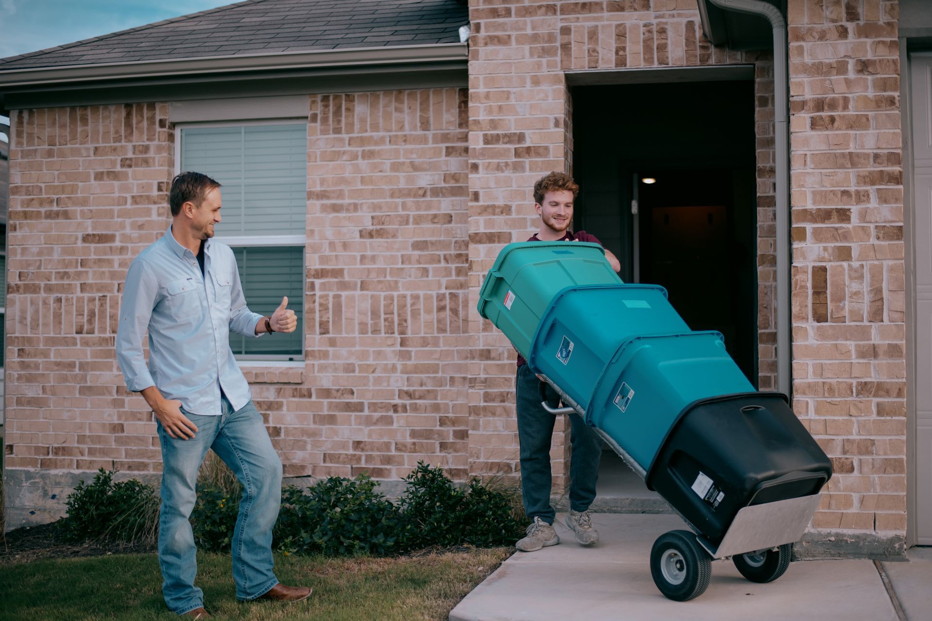 A man is pushing a cart full of trash cans into a house.