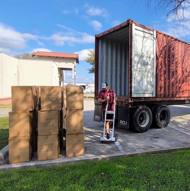 A man is loading boxes into a red shipping container.
