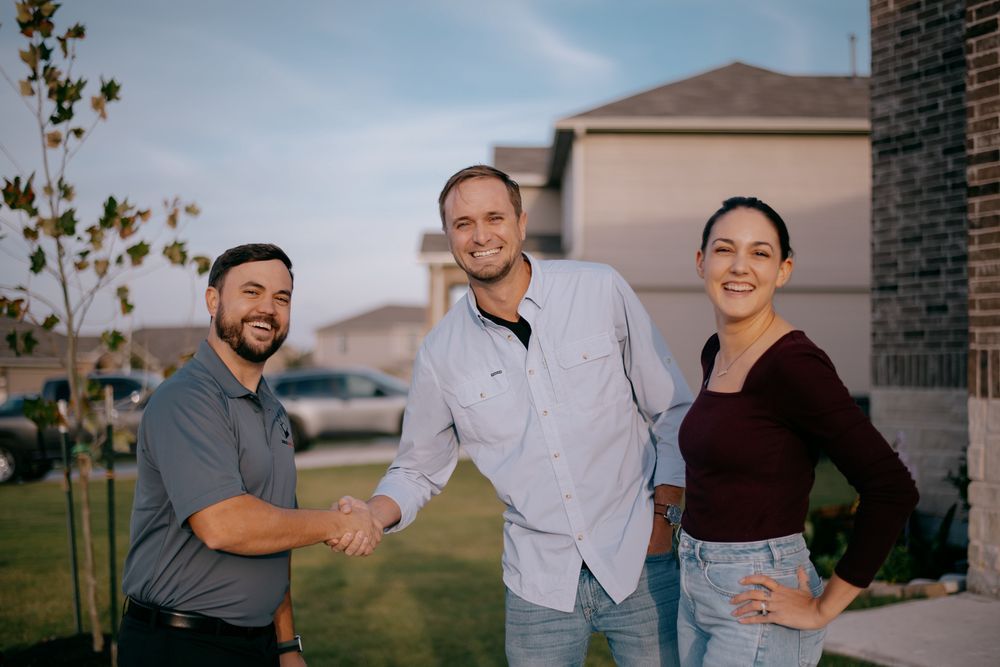 A man and a woman are shaking hands with a real estate agent in front of a house.