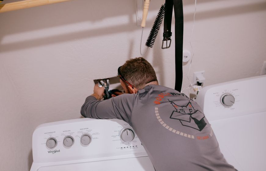 A man is fixing a washing machine in a laundry room.