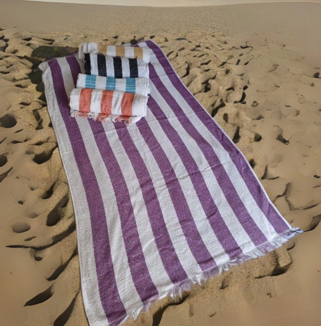 Toallas de rayas moradas y blancas en una playa de arena