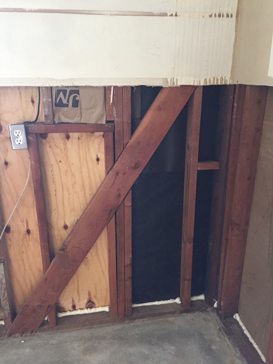 Interior wall partially deconstructed, revealing wooden frame and diagonal support beam.