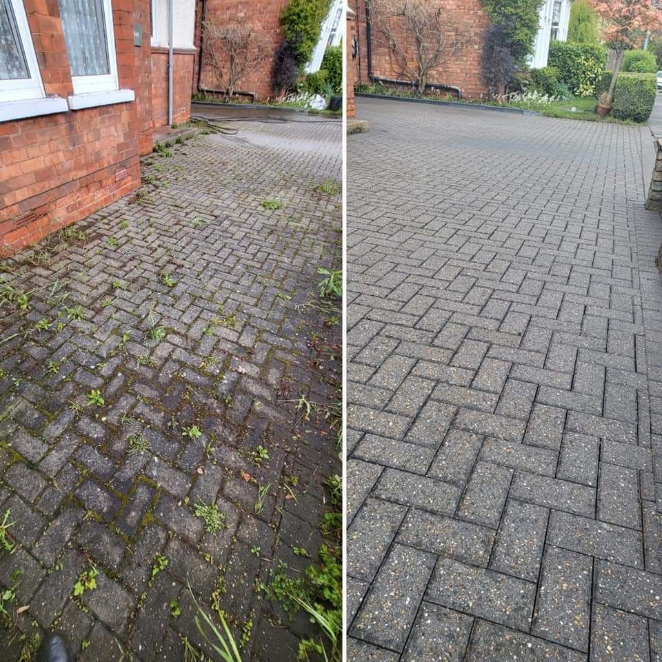 Man pressure washing a brick driveway in front of a house.