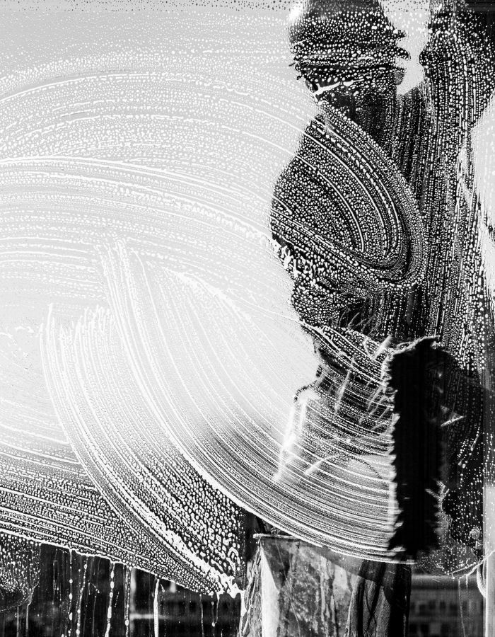 Cleaning a window with suds and a brush.