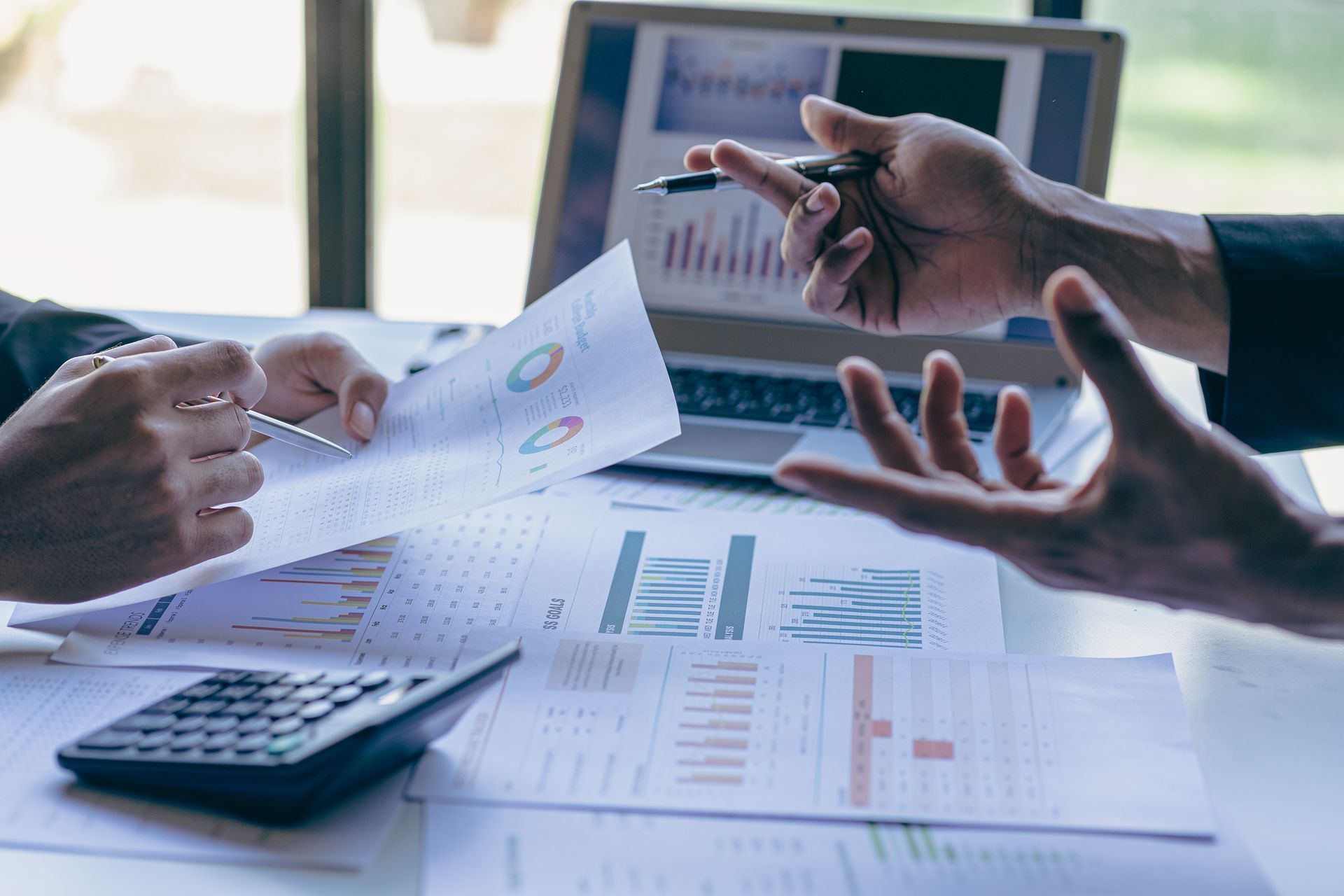 A certified public accountant reviewing financial charts and reports with a client at an office desk