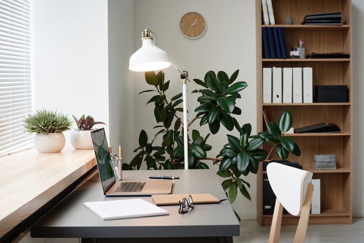 A desk with a laptop and a lamp on it in a home office.