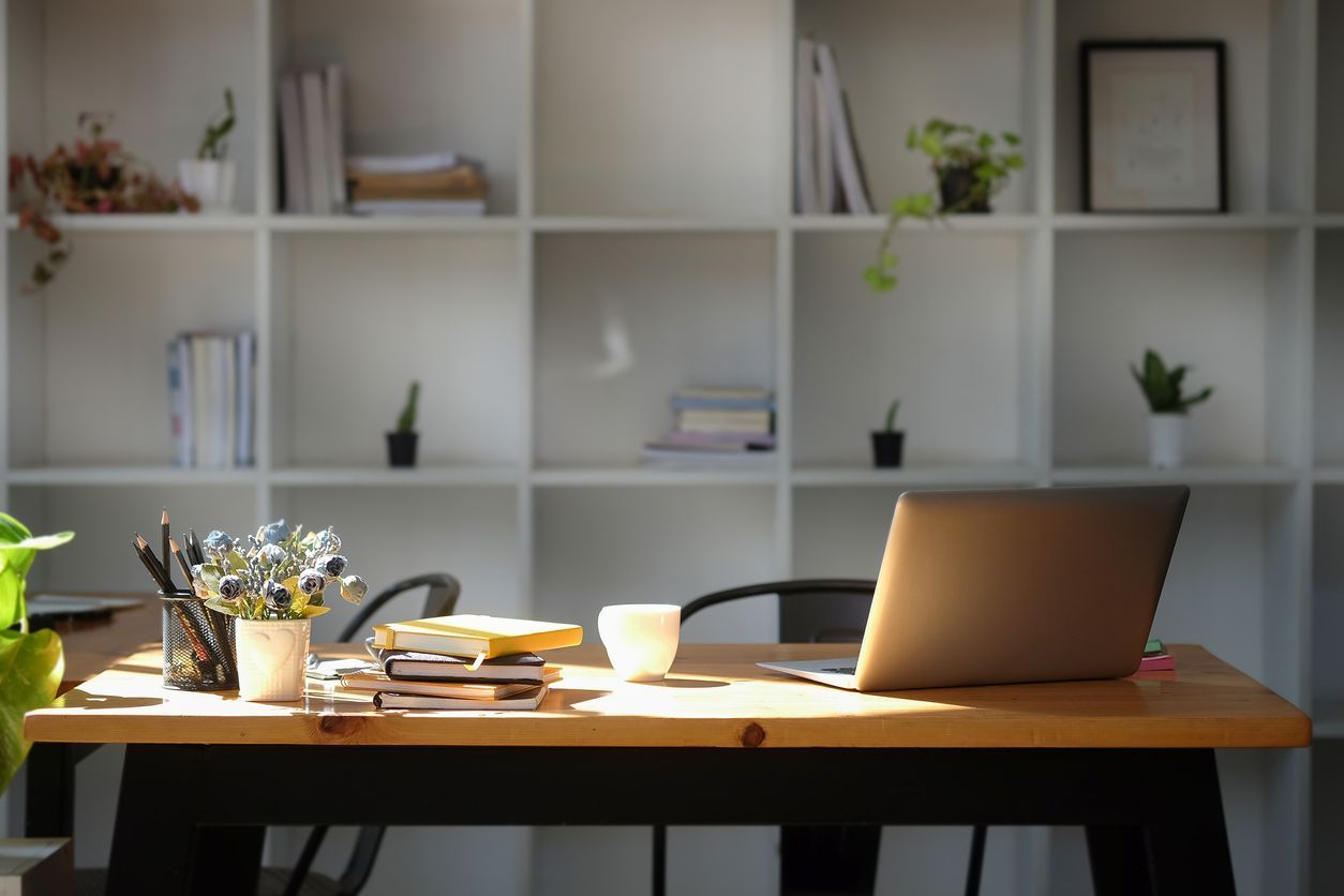 A wooden desk with a laptop on it in an office.