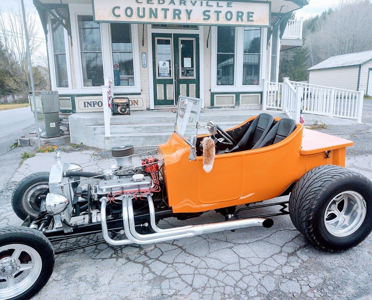 An orange car is parked in front of a country store
