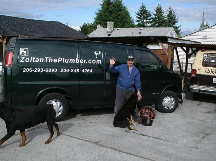 A man waves next to a dark green 