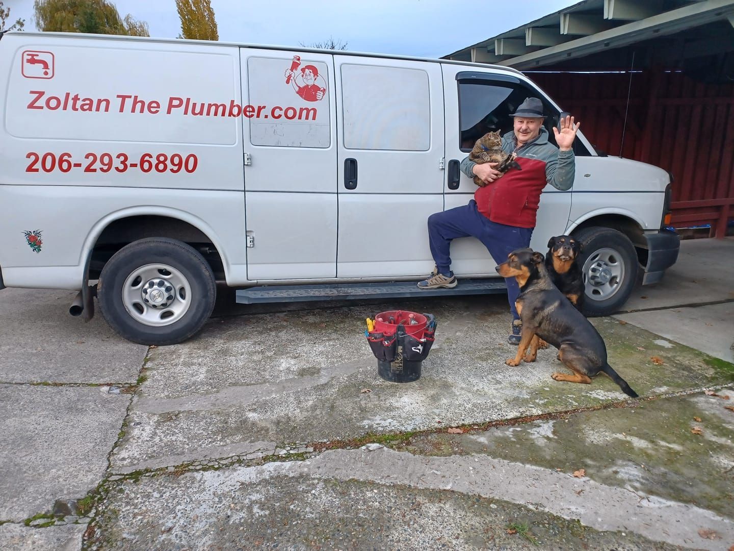 White water heater mounted on tiled wall, with flexible braided hoses connected to it.