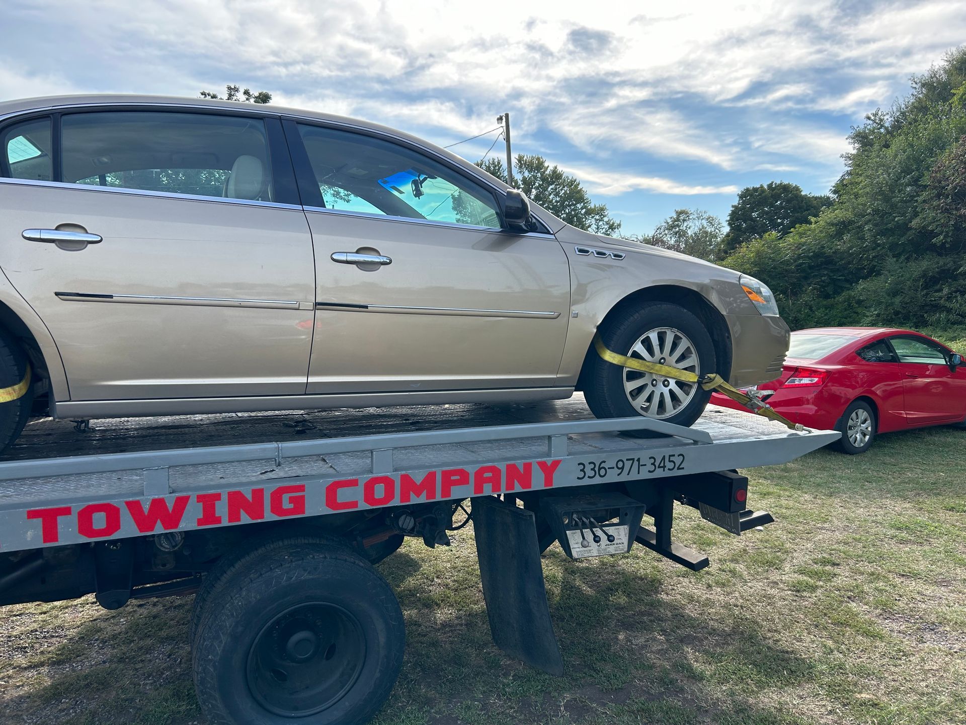 A car is sitting on top of a towing company truck.