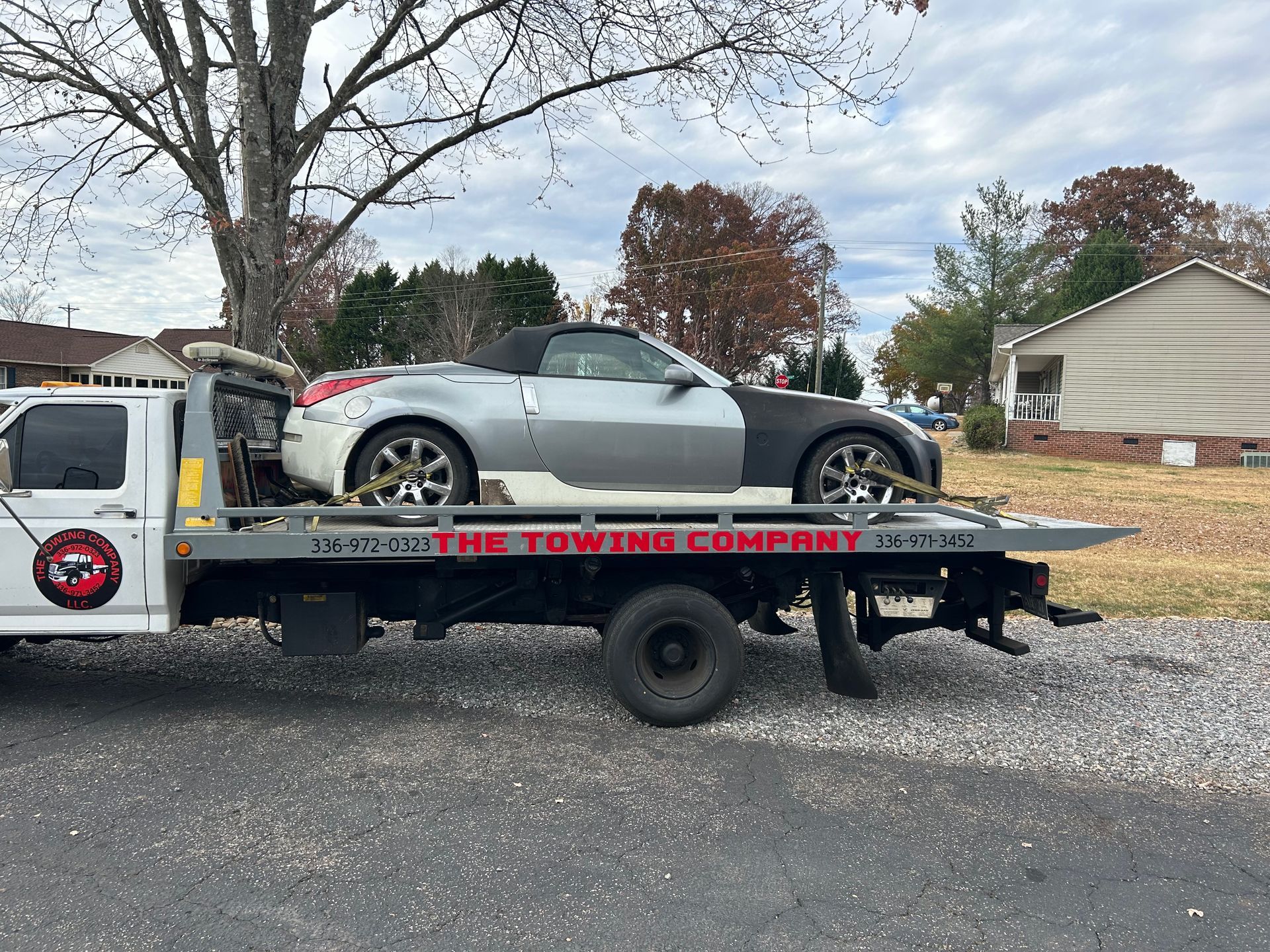 A car is being towed by a towing company truck.