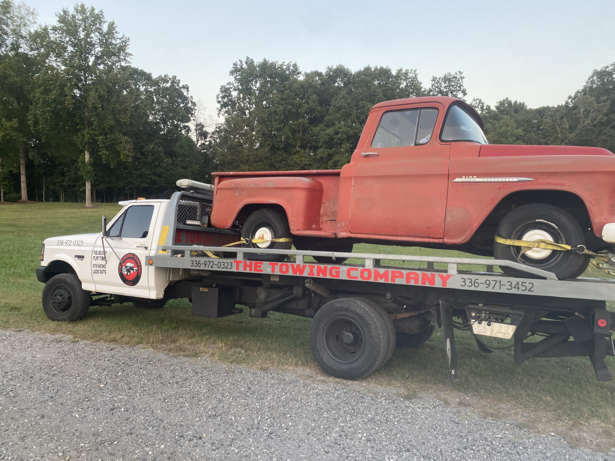 A red truck is being towed by a tow truck.