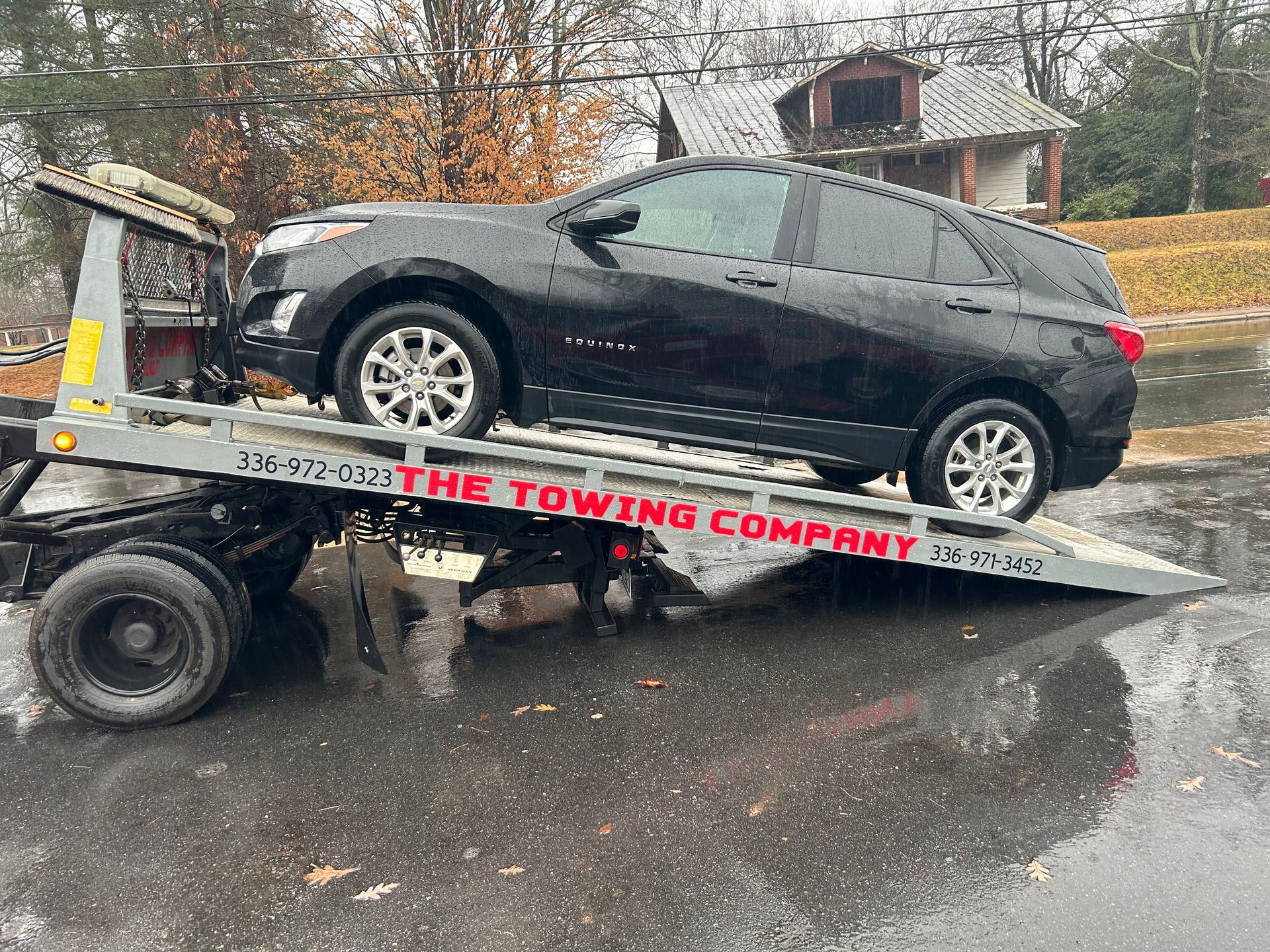 A black suv is sitting on top of a towing truck.
