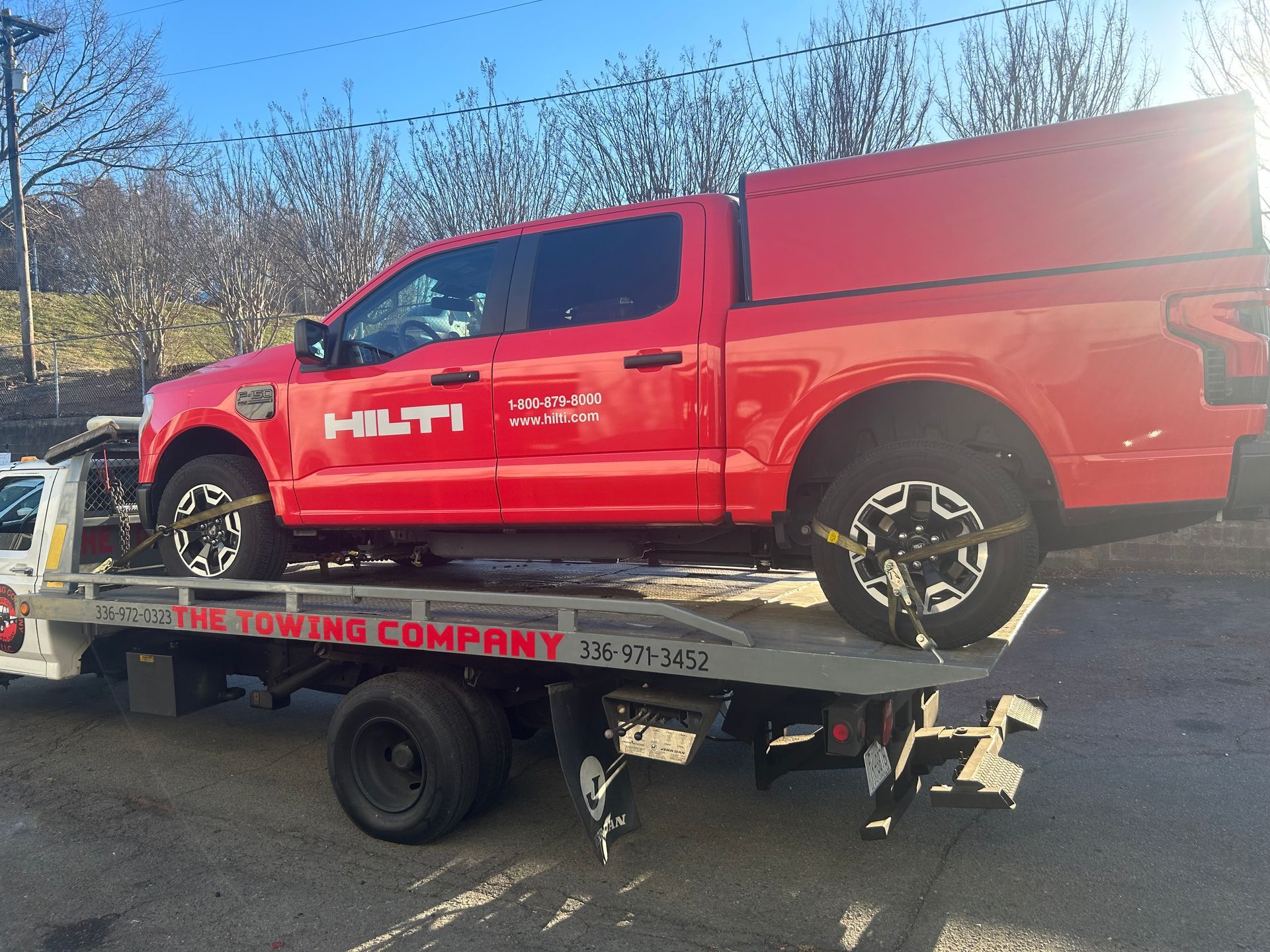 A red truck is being towed by a towing company
