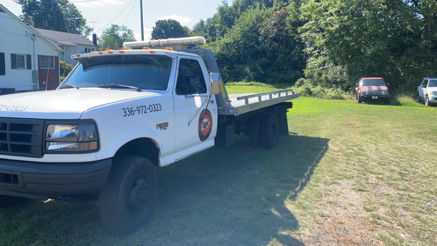 A white tow truck is parked in a grassy field.