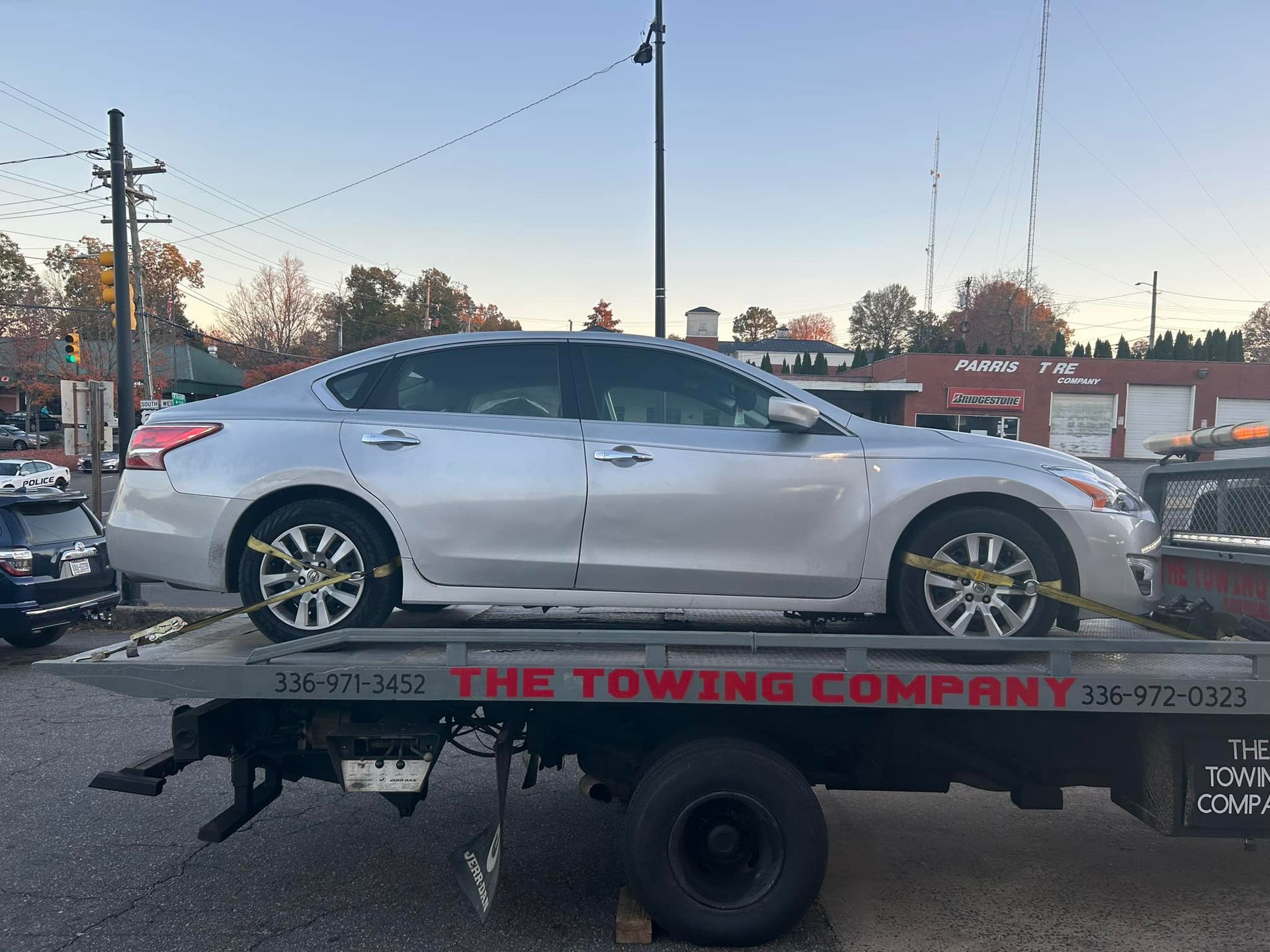 A silver car is sitting on top of a towing truck.