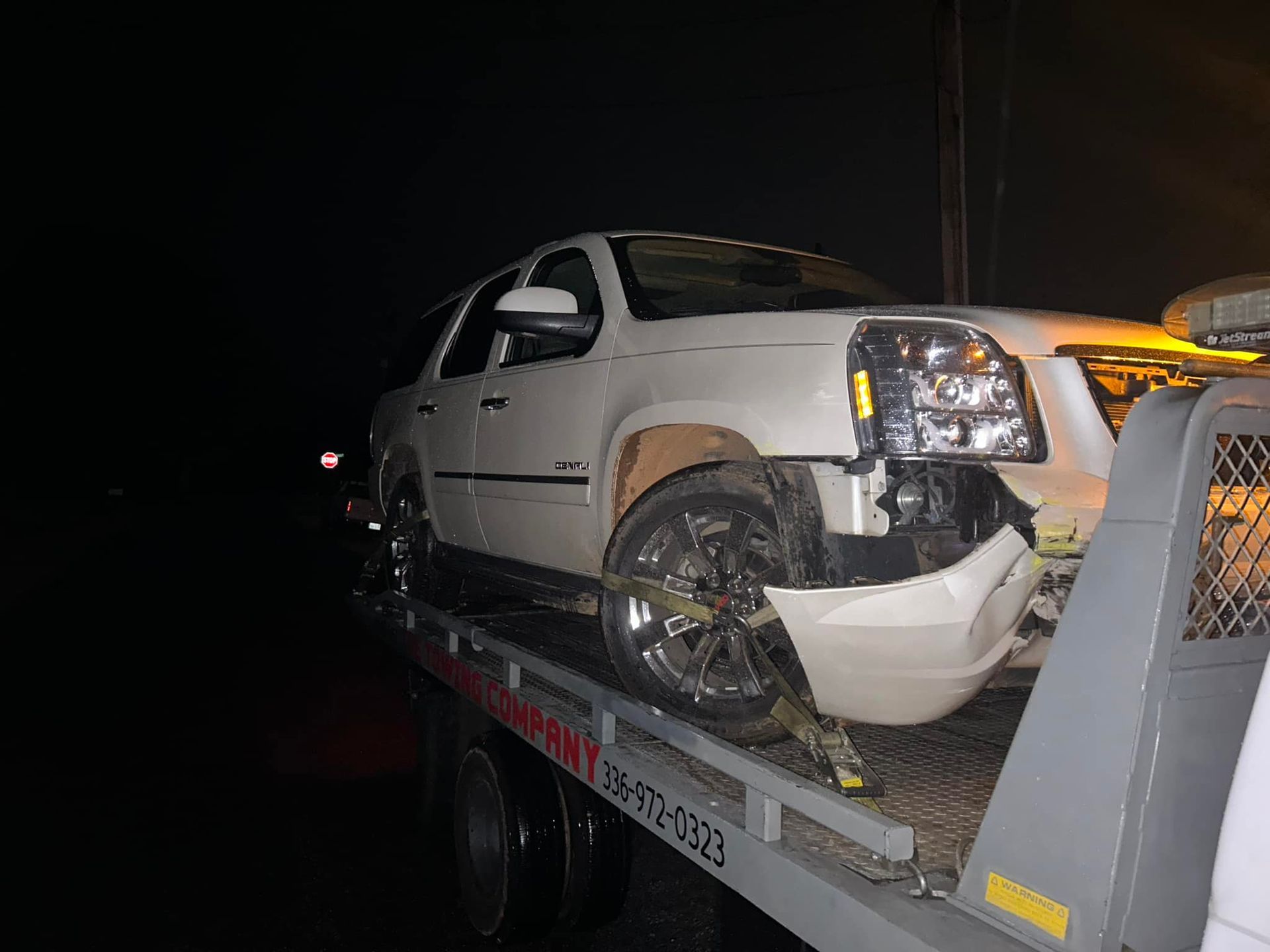 A white car is sitting on top of a tow truck.