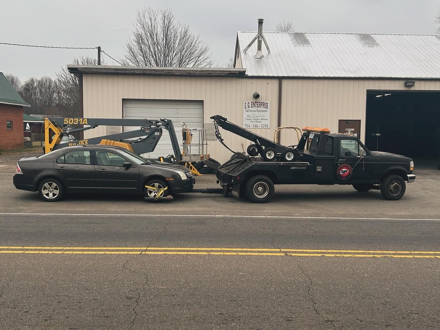 A black car is being towed by a tow truck