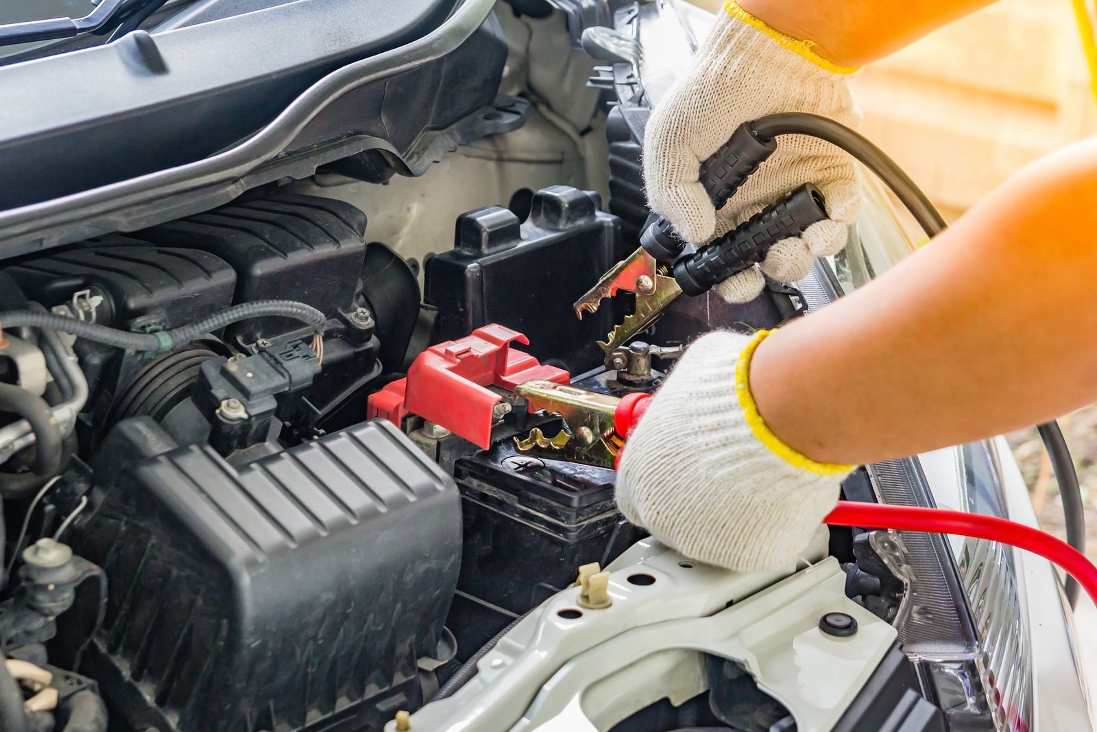 A person is charging a car battery with a jump starter.