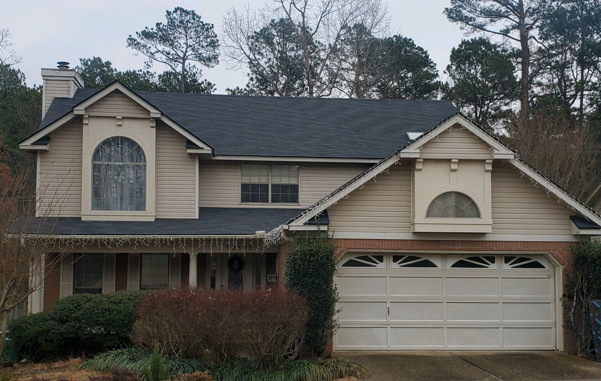 A house with a white garage door and a black roof