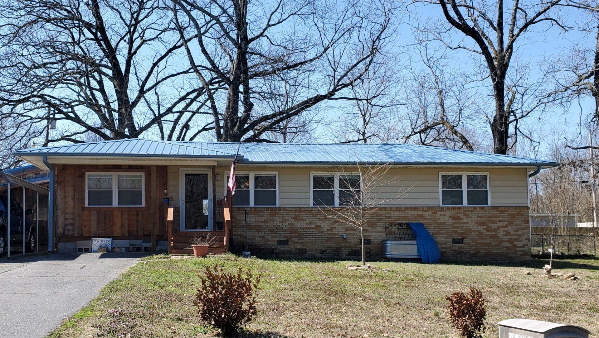 A small house with a blue roof and trees in the background.