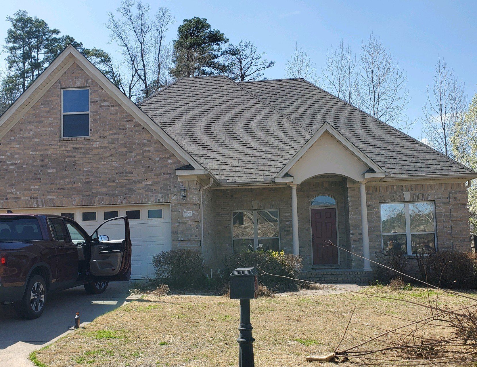 A red truck is parked in front of a brick house.