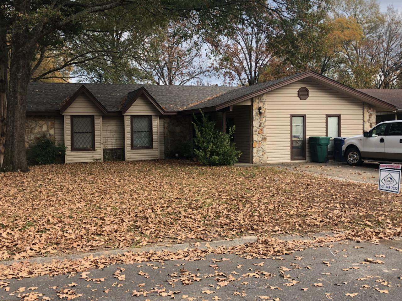 A house with a lot of leaves on the ground in front of it