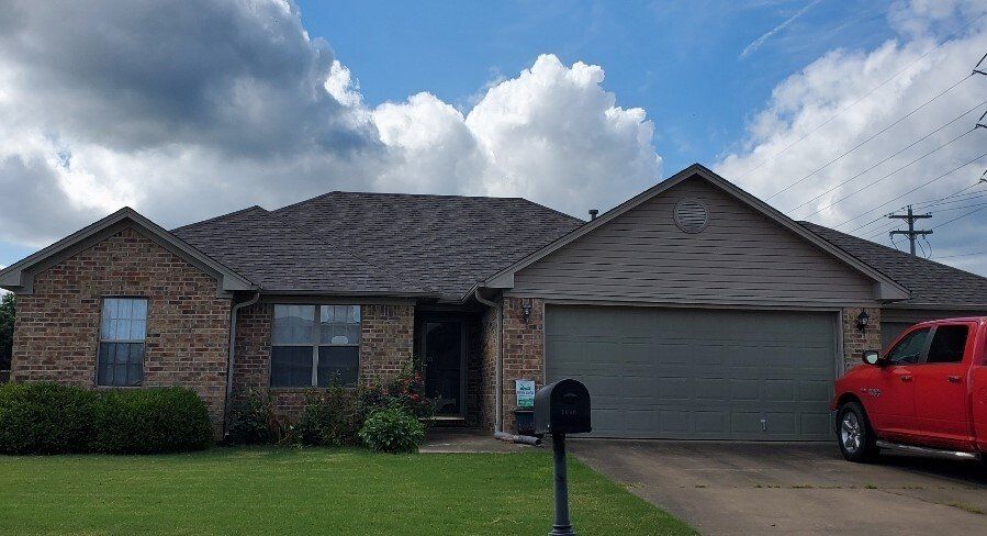 A red truck is parked in front of a brick house.