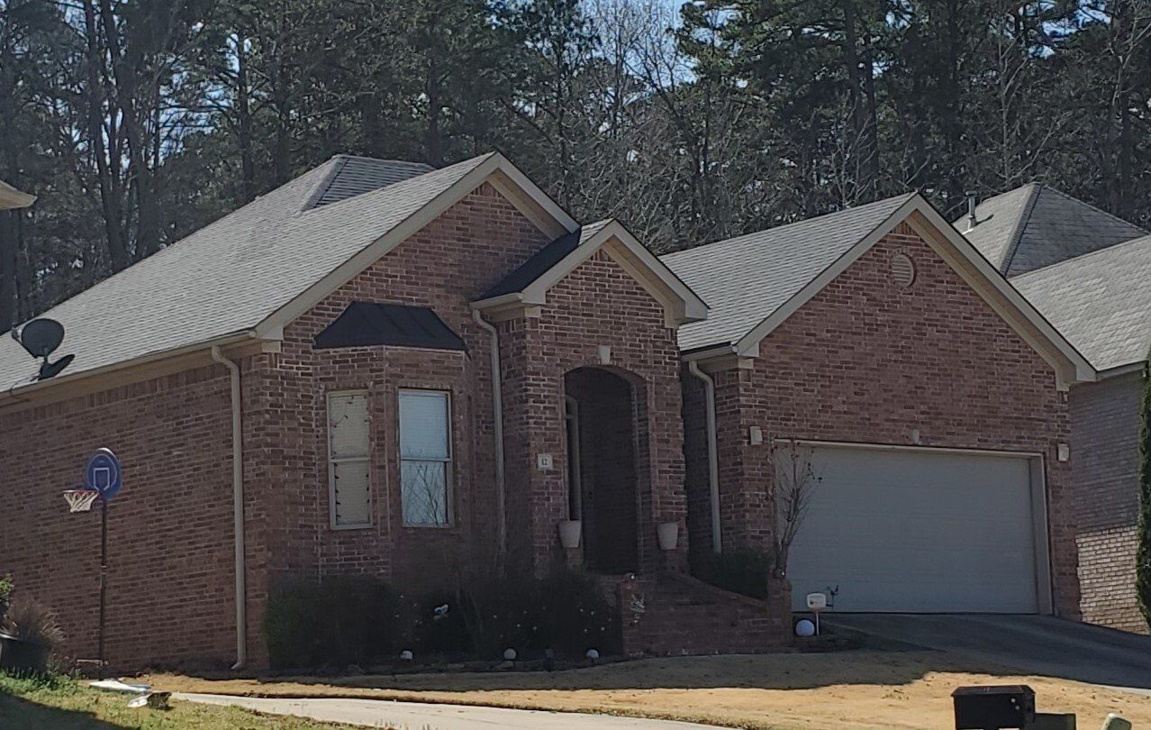 A brick house with a white garage door and a satellite dish on the roof.