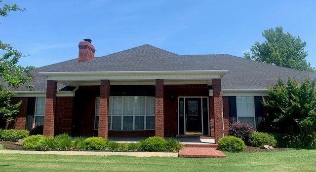 A brick house with a gray roof and a chimney