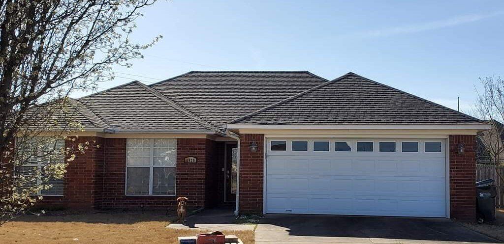 A brick house with a white garage door and a fire hydrant in front of it.
