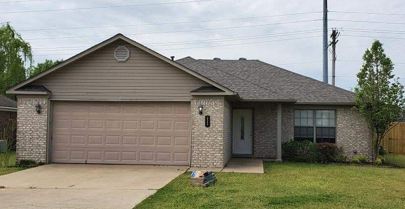 A brick house with a large garage and a gray roof.