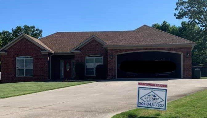 A brick house with a garage and a sign in front of it.