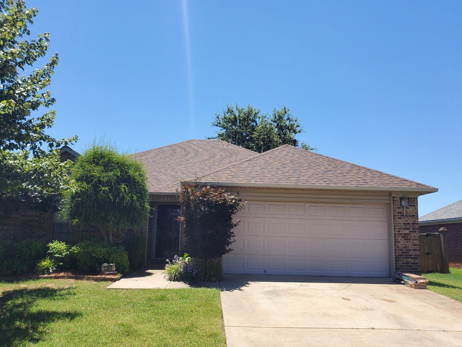 A white house with a brown roof and a driveway in front of it.