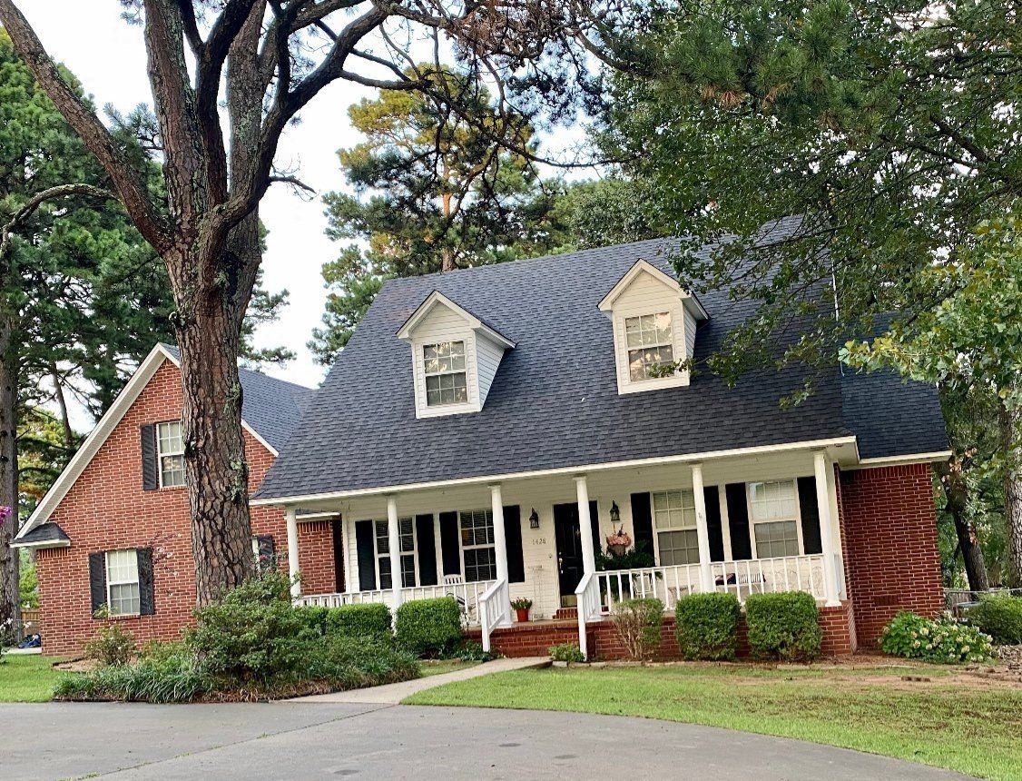 A large brick house with a black roof and a porch