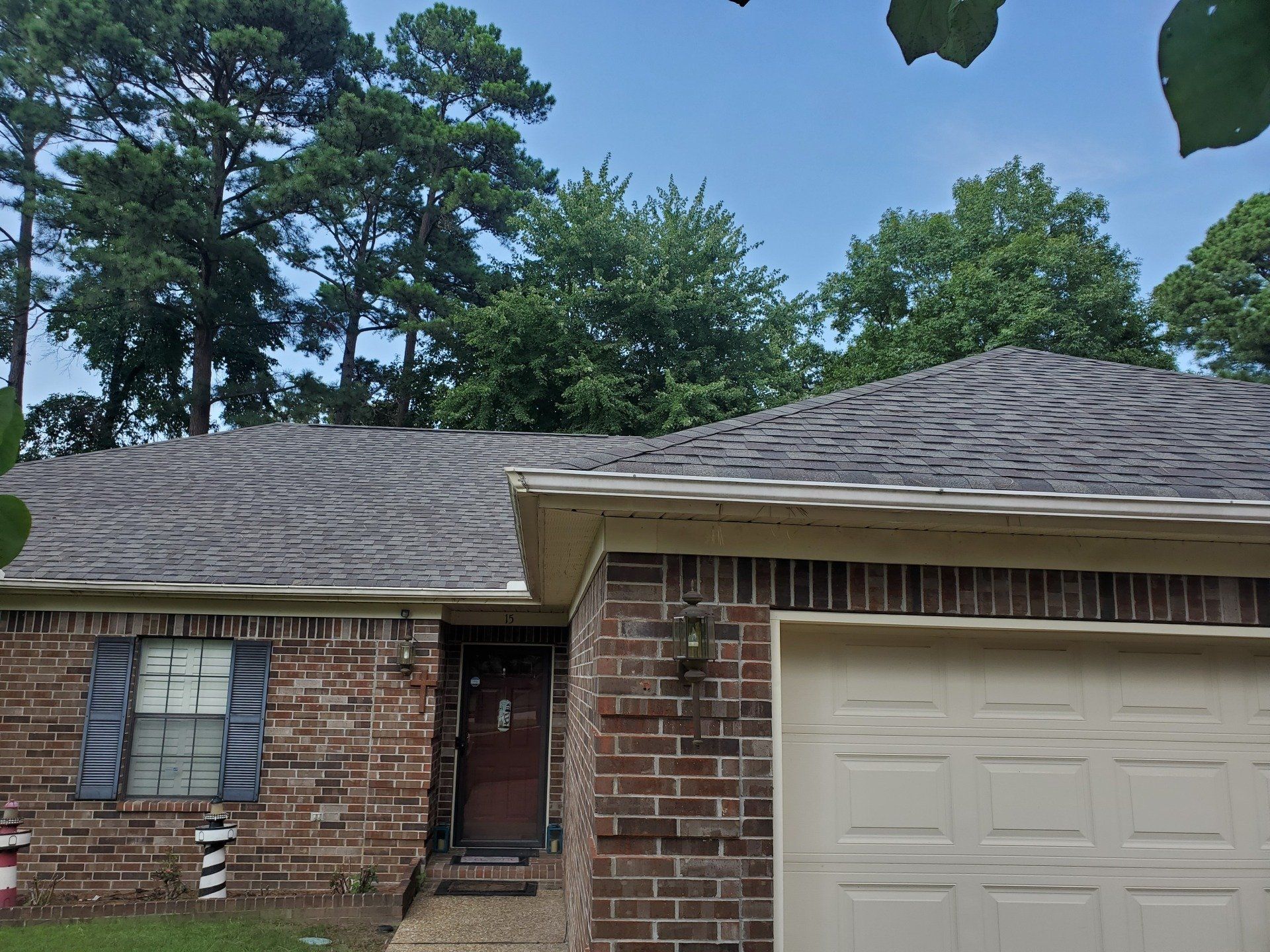 A brick house with a garage and trees in the background.