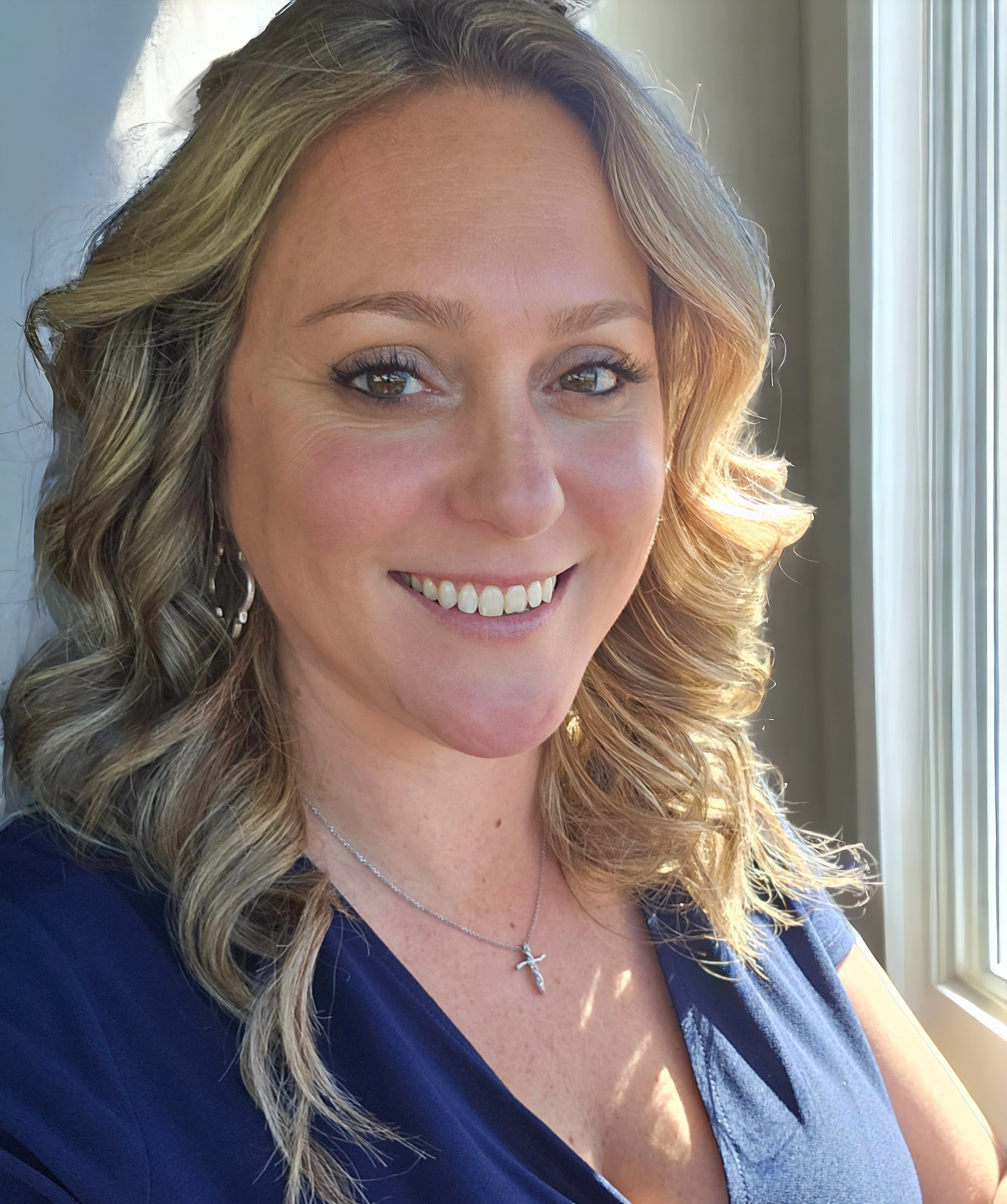 A woman in a blue shirt is smiling for the camera.