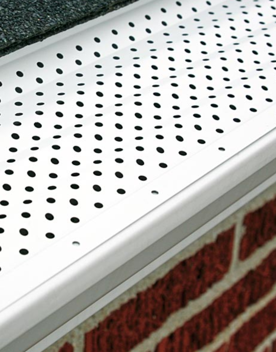 A gutter with holes in it is on a brick wall