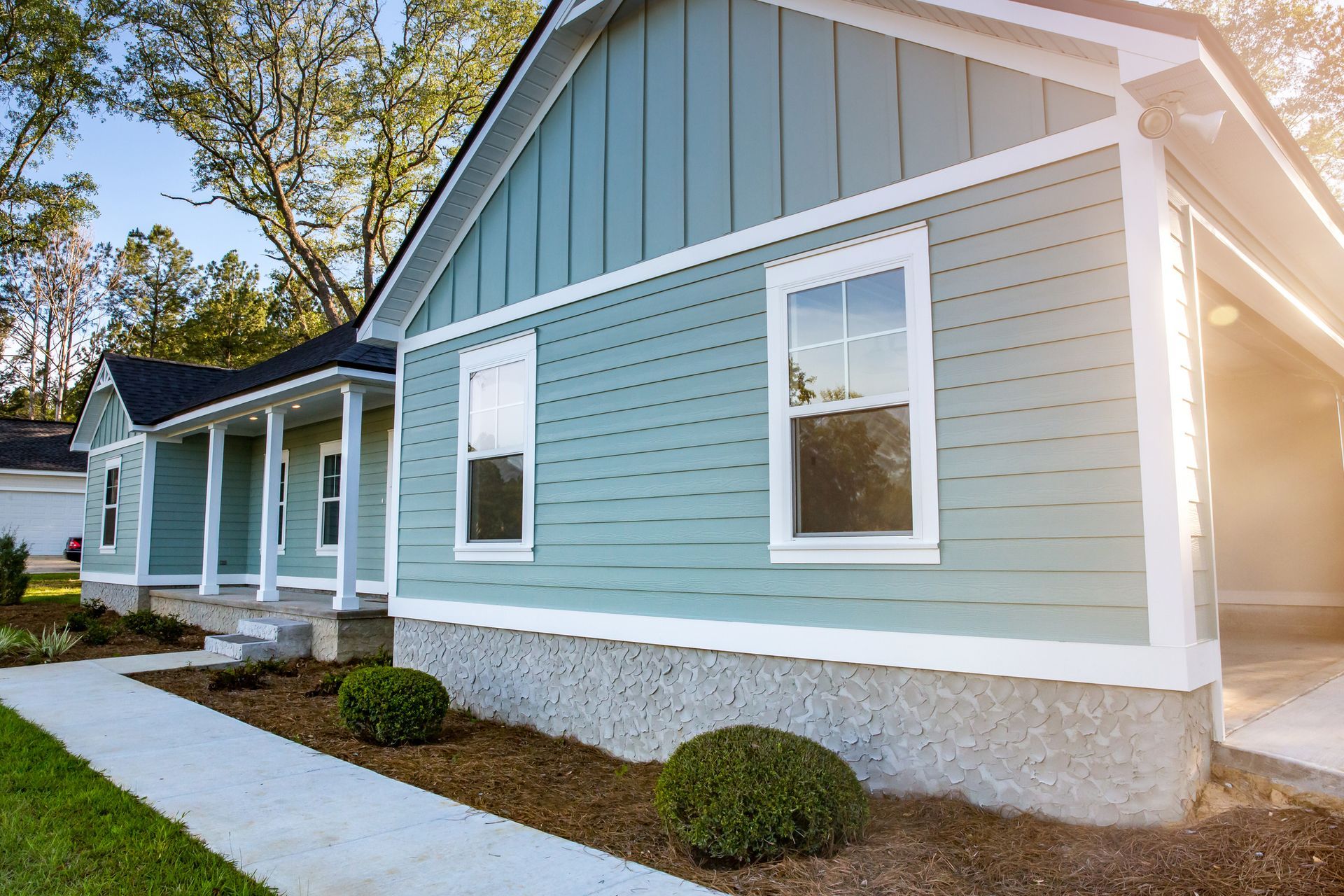 A blue and white house with a porch and a sidewalk in front of it.