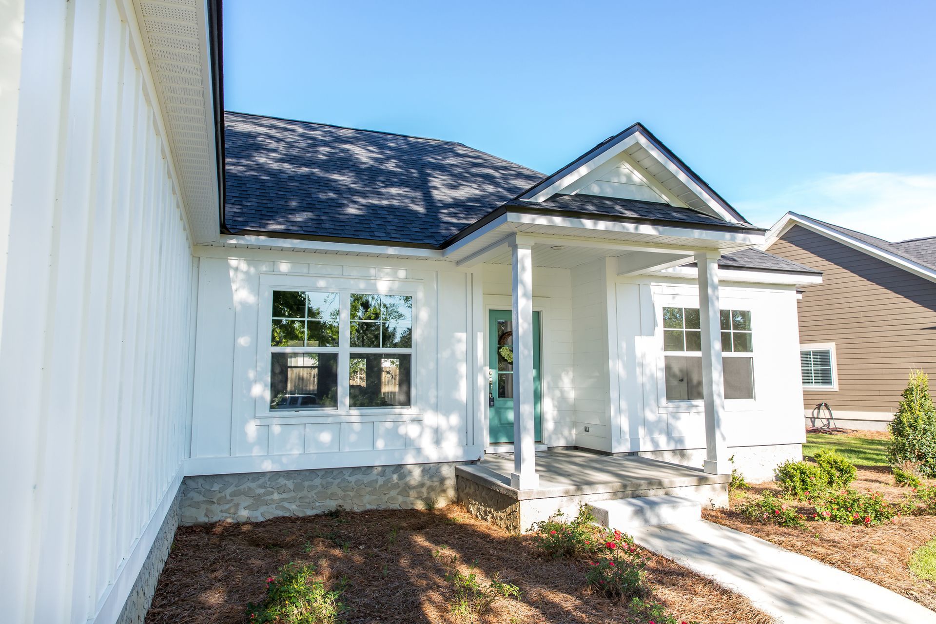 A white house with a porch and a blue door.