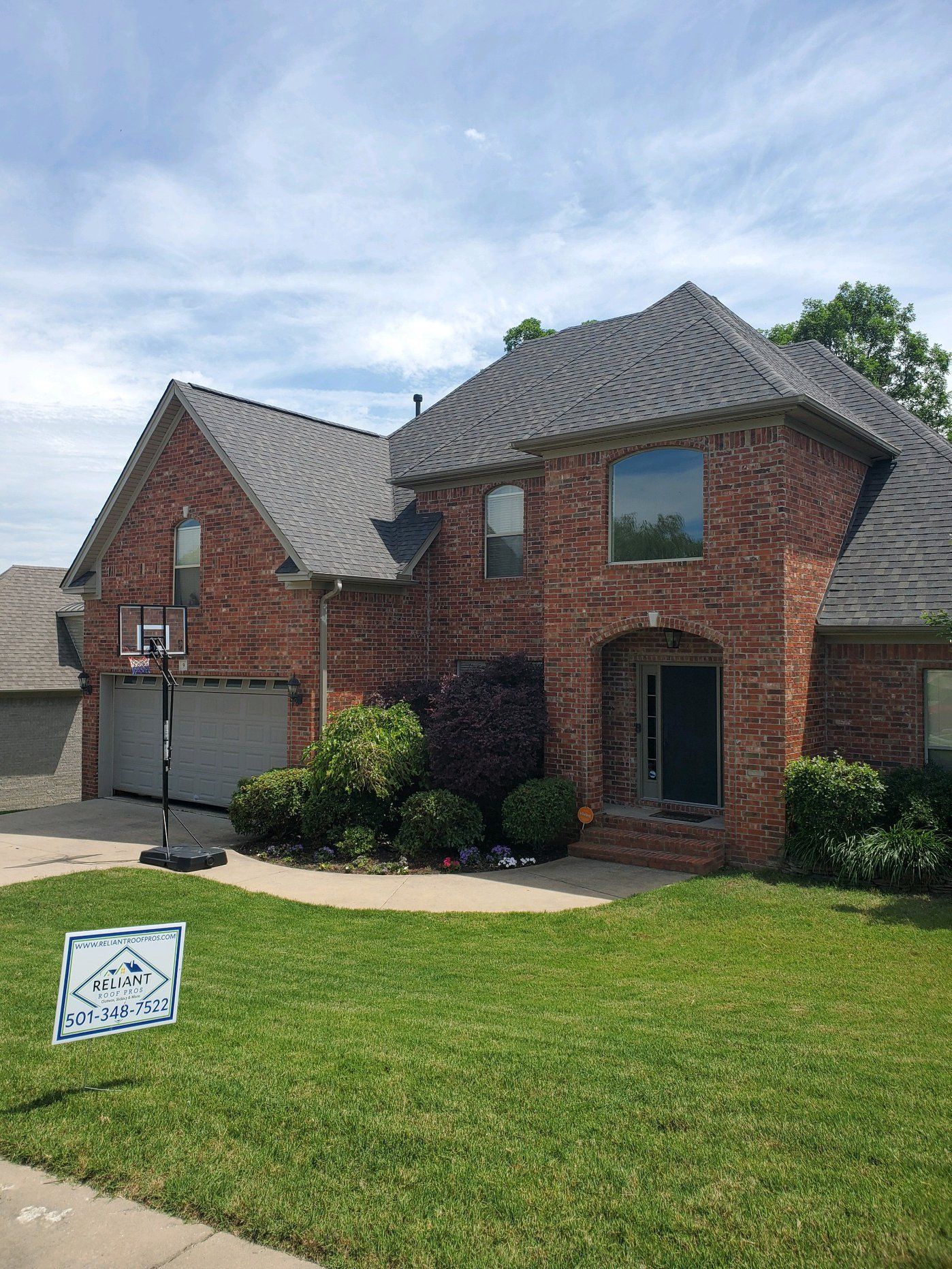 A large brick house with a basketball hoop in front of it.
