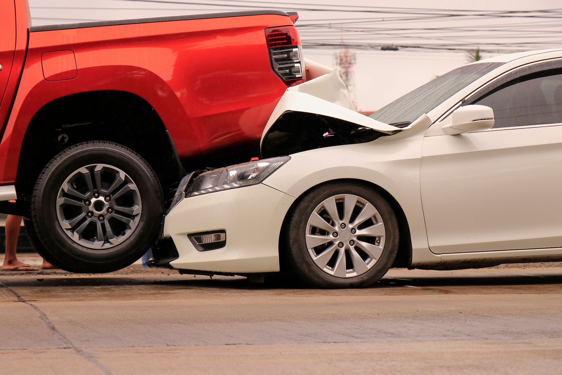 Red pickup truck rear-ended a white sedan in a collision on the road.