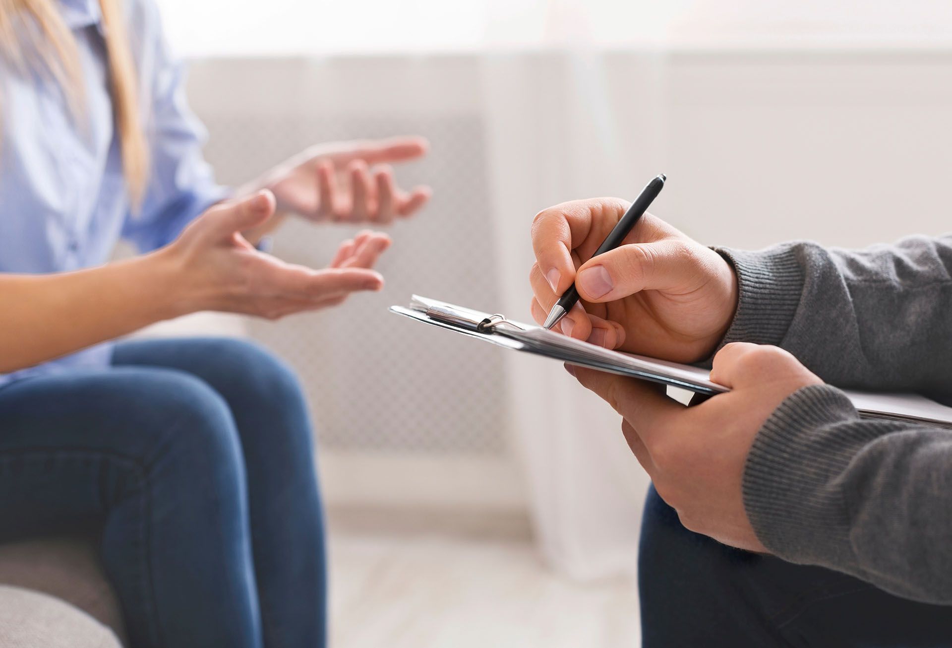 A man is writing on a clipboard while talking to a woman.