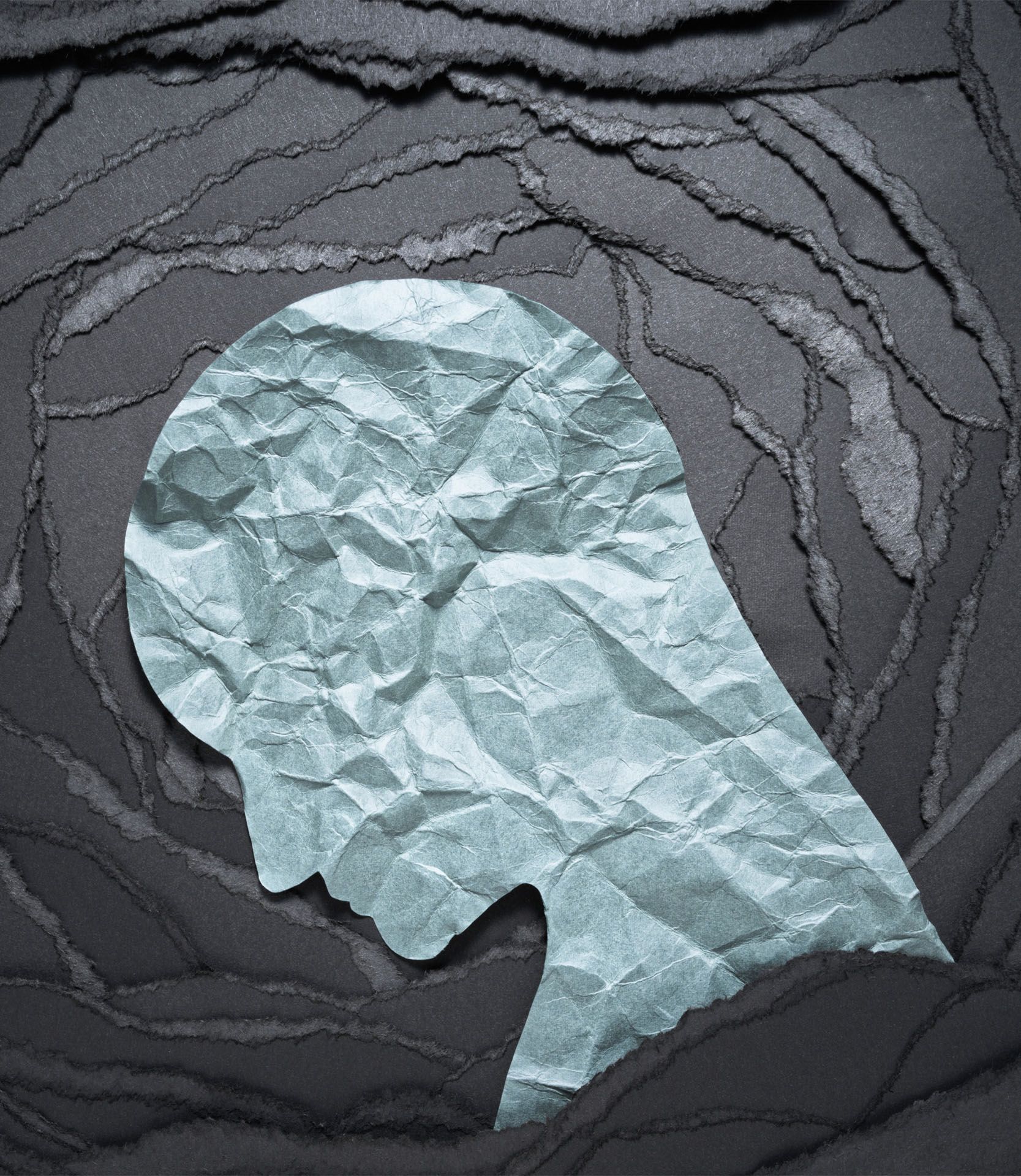 A silhouette of a person 's head made out of crumpled paper