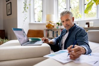 Man with grey hair working on laptop.