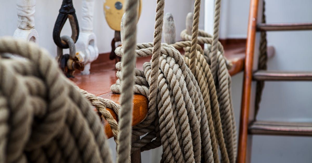 A bunch of ropes hanging from a ladder on a boat.